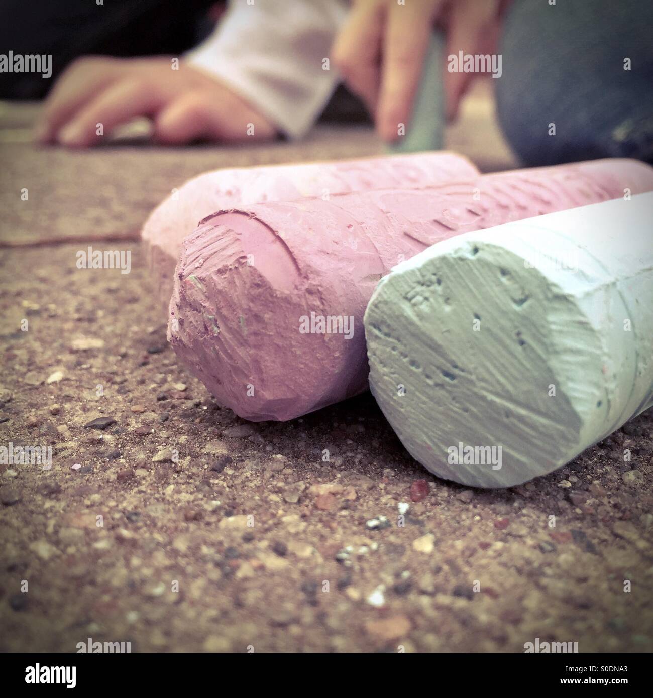 Sidewalk chalk with child artists in the background Stock Photo