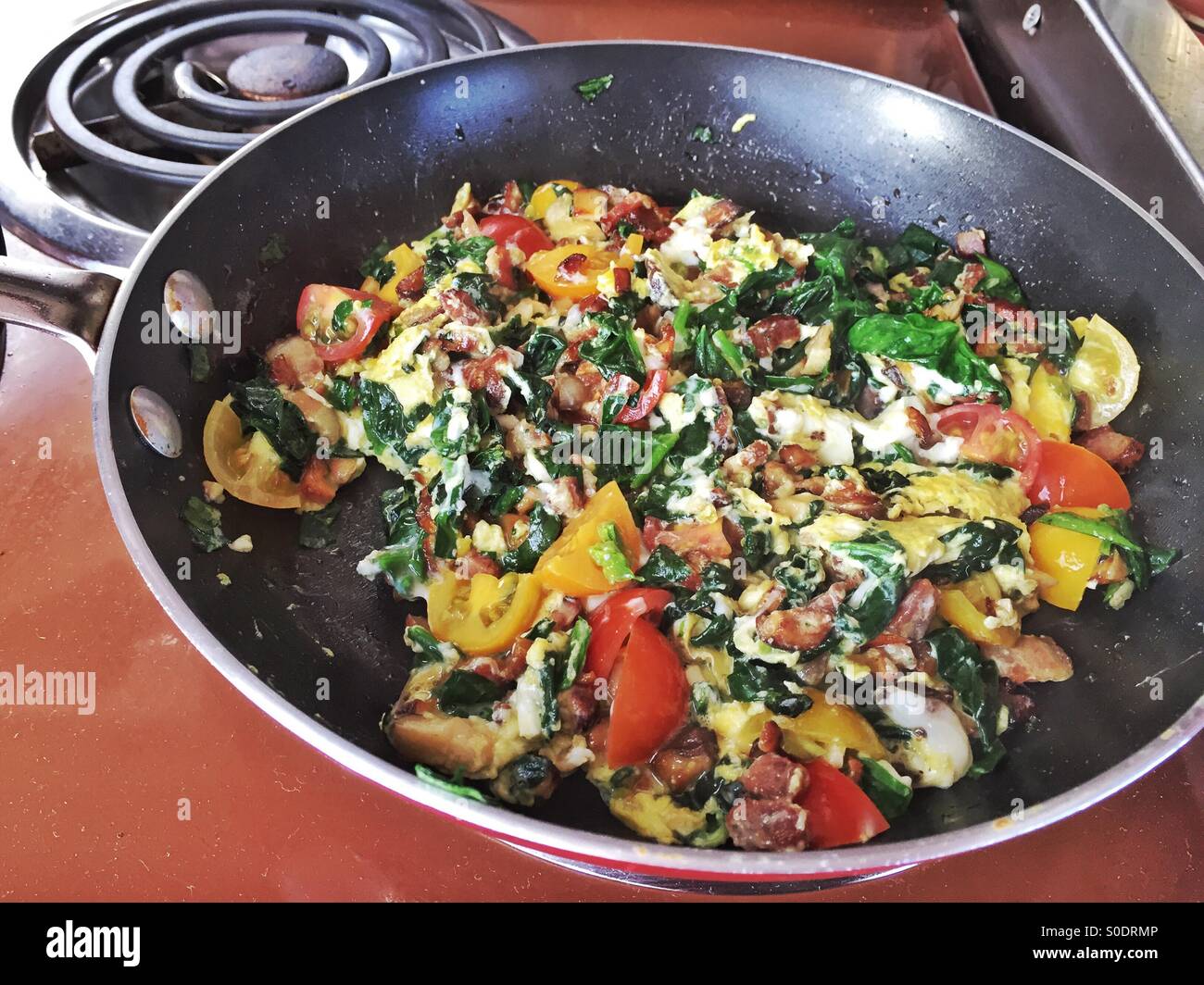 Breakfast scramble with bacon, shiitake mushrooms, spinach, and tomatoes . Stock Photo