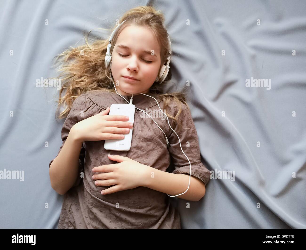 It sounds like a dream. Young girl lying on the bed and dreaming about something with closed eyes. Stock Photo