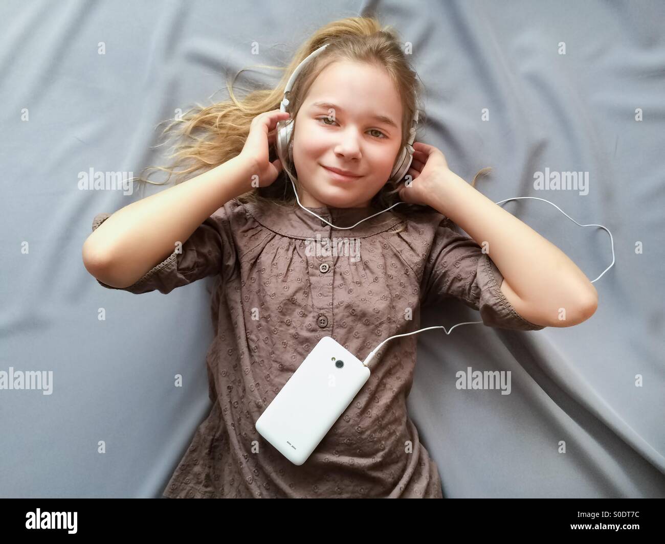 Young girl lying on the bed and listening to music Stock Photo - Alamy