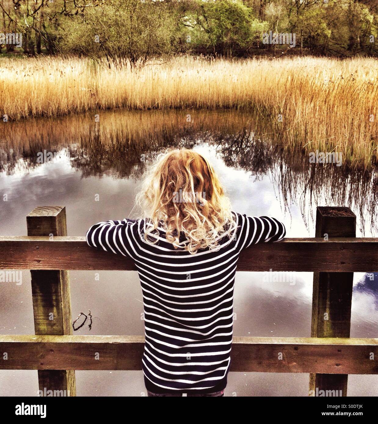 Young girl looking out over pond at Yarrow Valley near Chorley in Lancashire Stock Photo