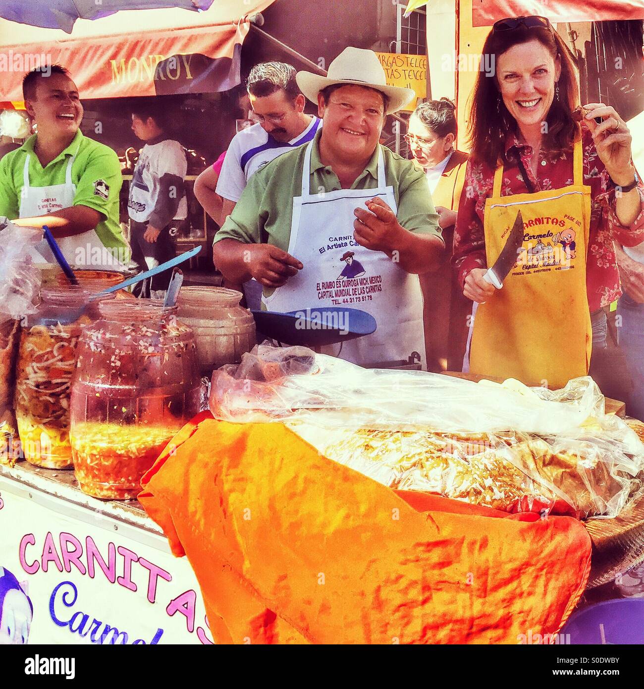 A happy tourist enjoys some hands on fun at a carnitas street vendors stand in Quiroga, Michoacan. Stock Photo