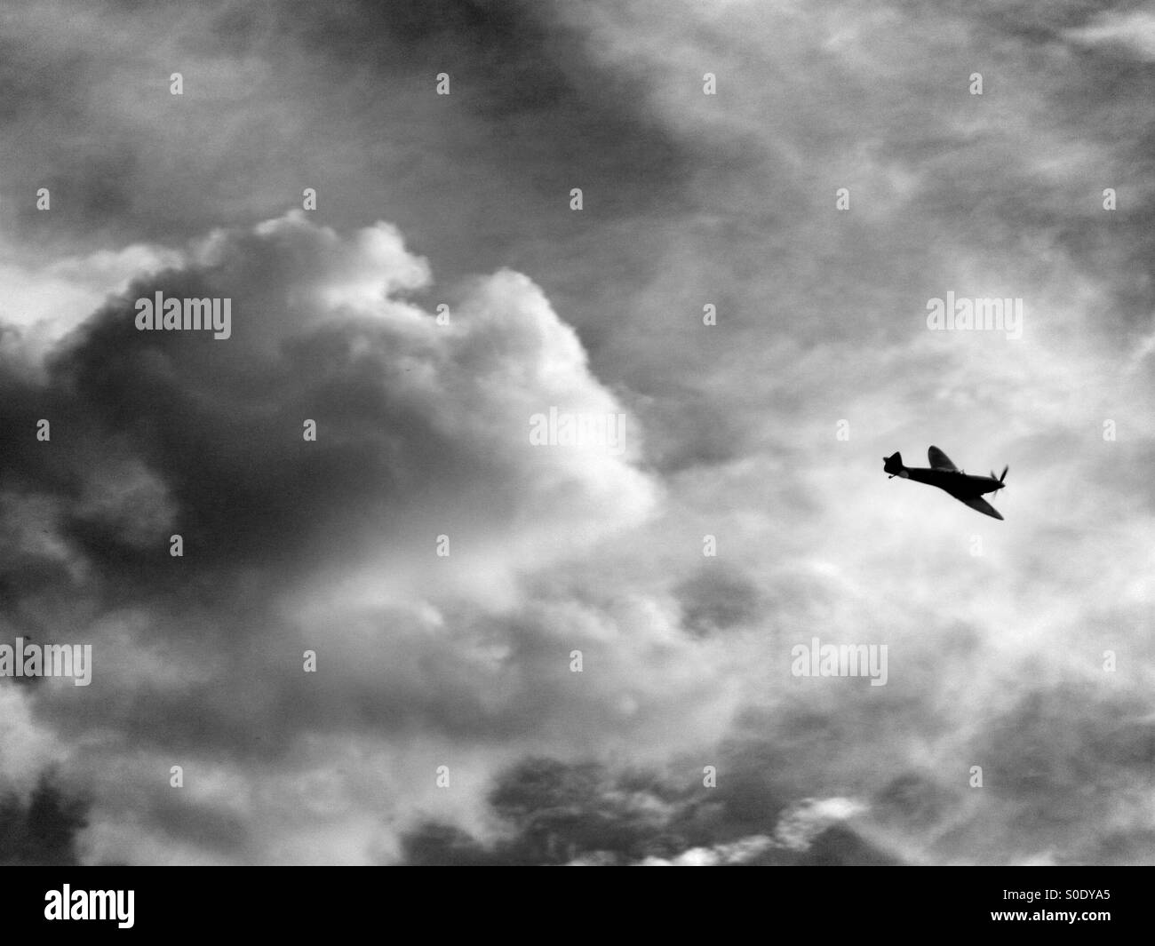 Spitfire flying with big clouds in background Stock Photo