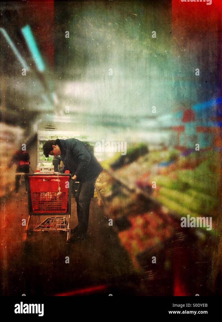 Man leaning over his shopping cart in a supermarket - Smartphone Captured Stock Image