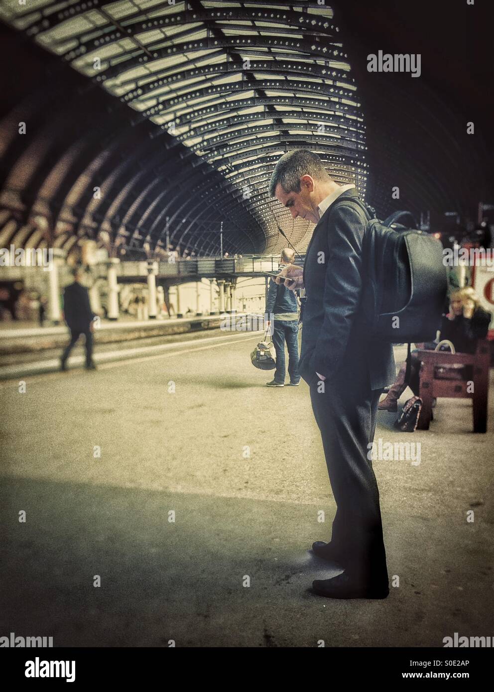 Commuter texting whilst waiting for train to arrive - Smartphone Captured Stock Image