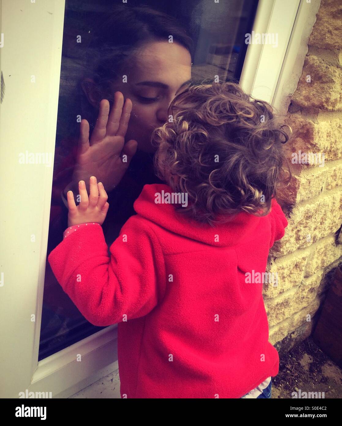 Sisters kissing through glass Stock Photo - Alamy