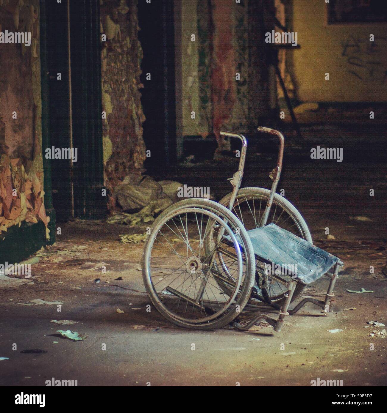 Eerie wheelchair in abandoned building Stock Photo