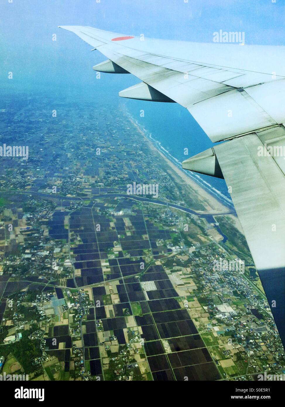 Aerial view of rice fields, farmland, forest, Pacific Ocean, seashore and residential areas of Chiba Prefecture in Japan as seen from window of All-Nippon Airways airplane. Stock Photo