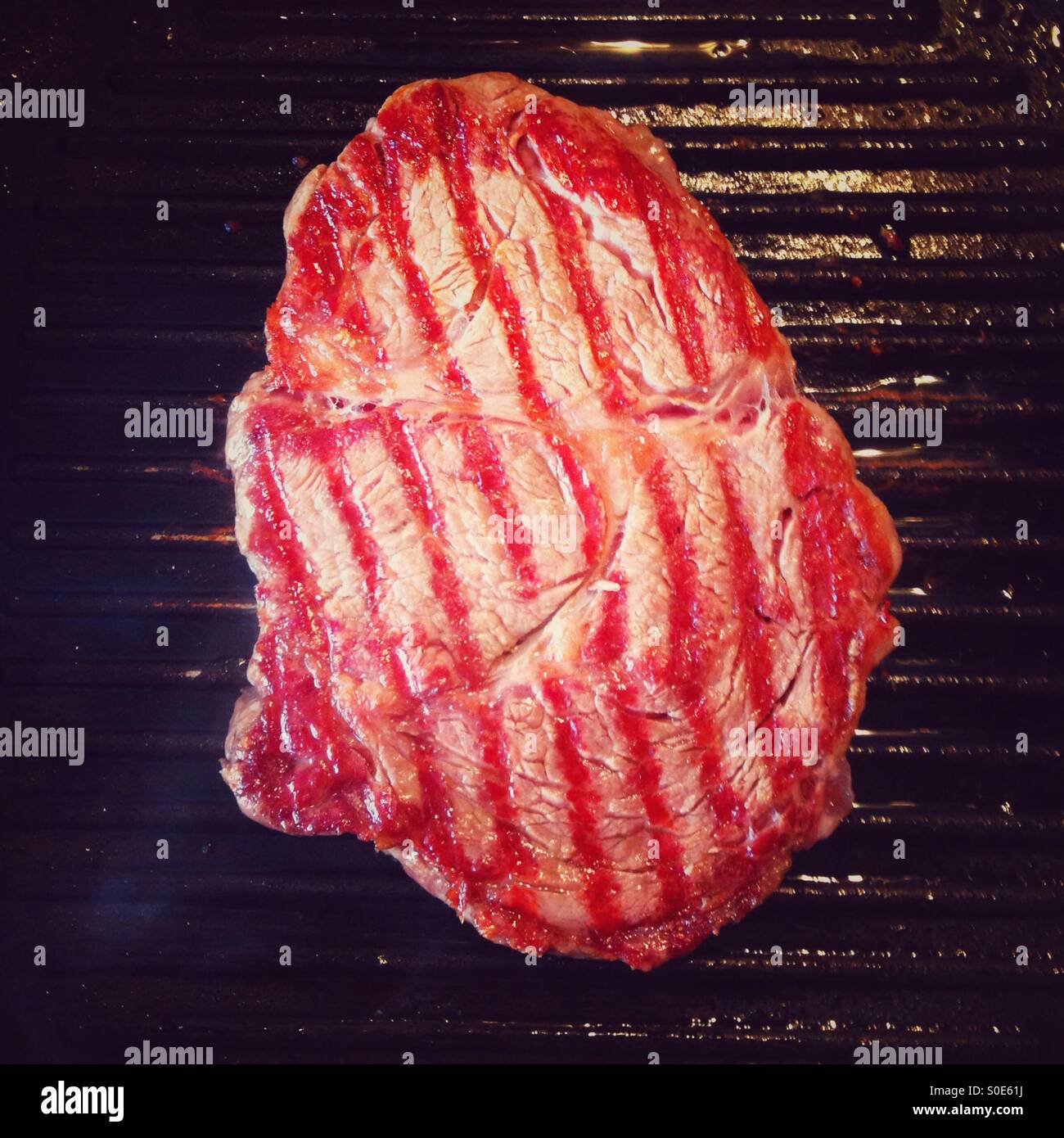 Rib eye steak cooking on a griddle pan Stock Photo Alamy