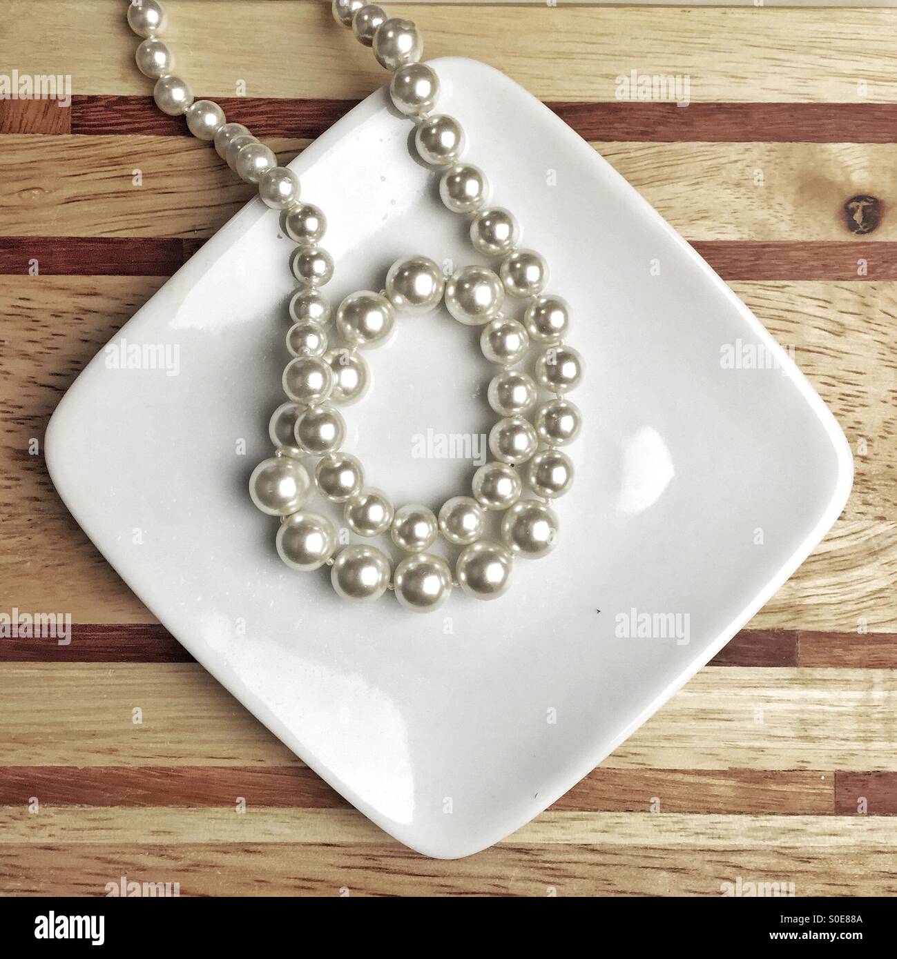 String of white pearls on a porcelain plate Stock Photo