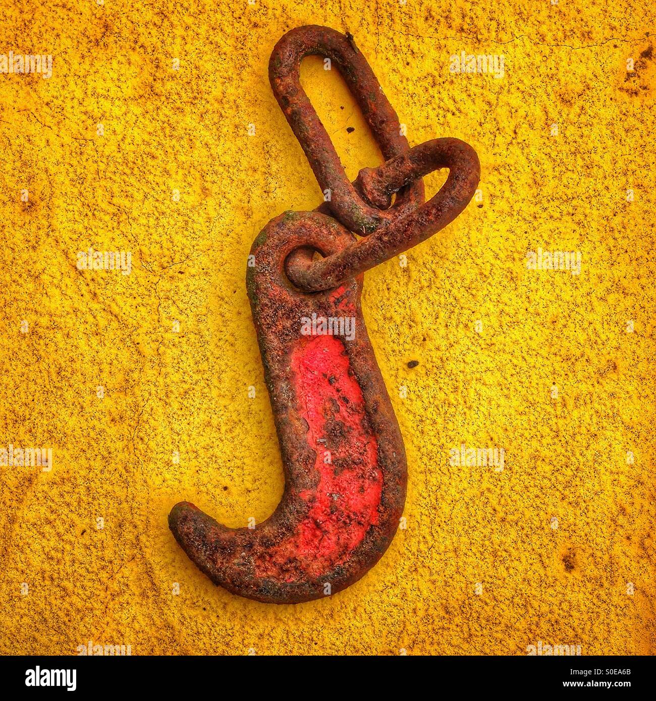 A rusty red hook on a yellow background Stock Photo Alamy