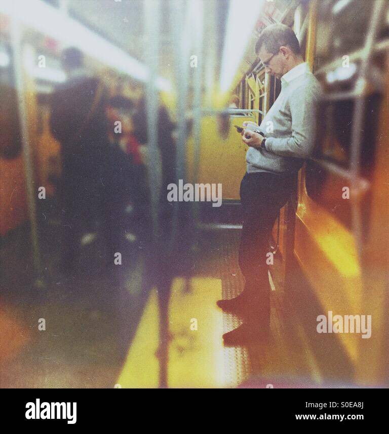Man consulting his smartphone in metro car - Smartphone Captured Stock Image