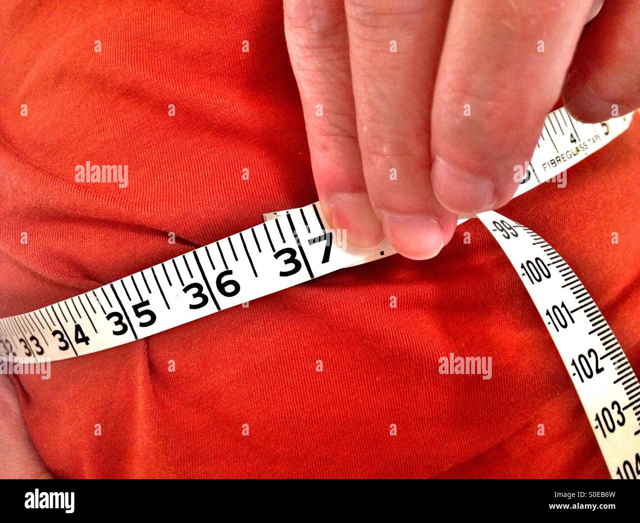 Man taking his waist measurement Stock Photo