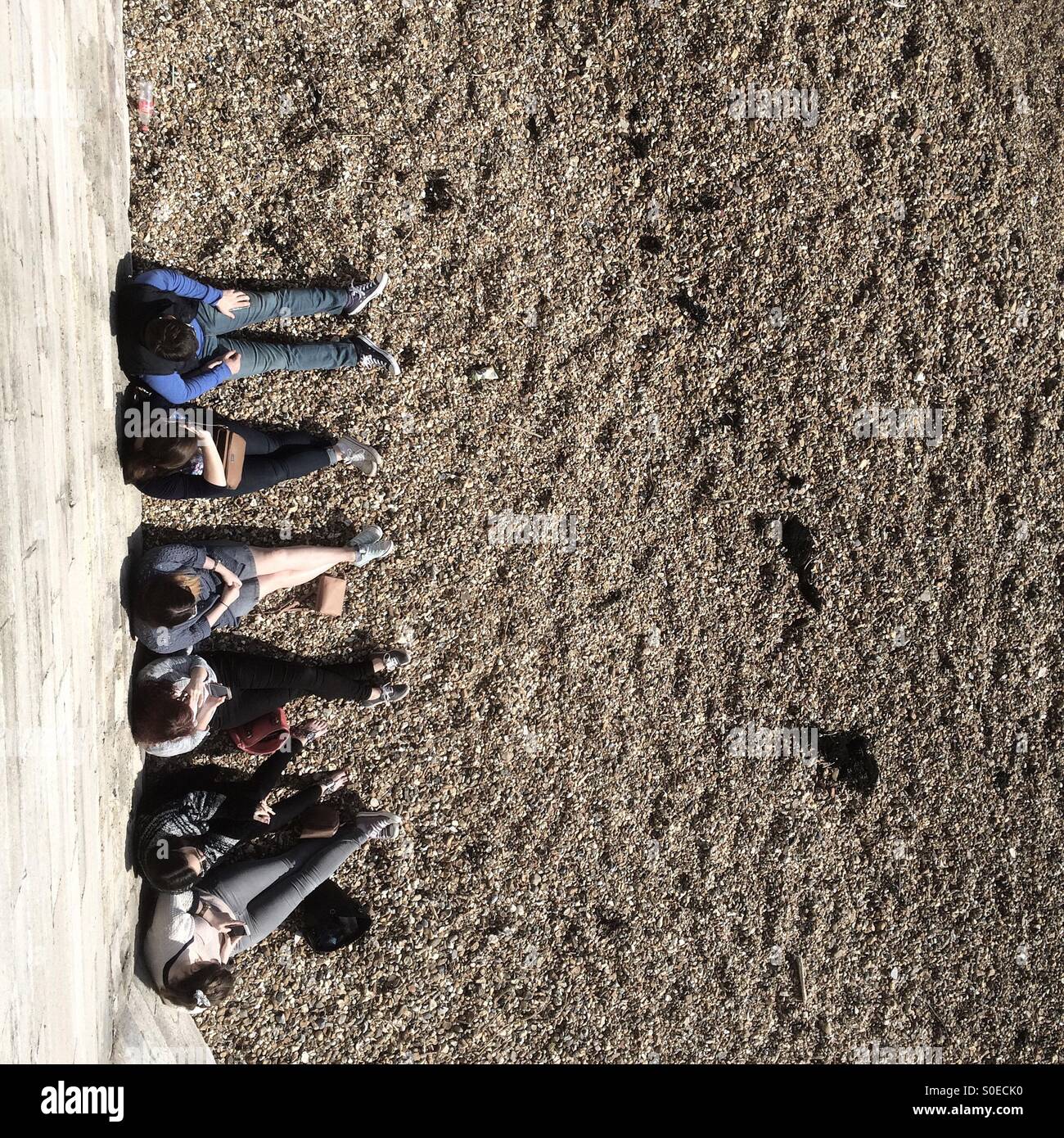 People sitting on the beach at Southsea overlooking Portsmouth Harbour entrance - Smartphone Captured Stock Image