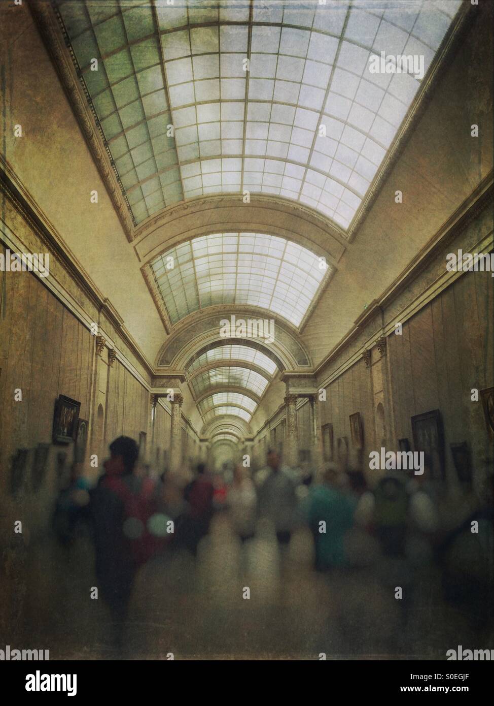 Crowd of tourists at the Grande Galerie or Grand Gallery in the Louvre museum in Paris, France. Vintage texture overlay. Stock Photo