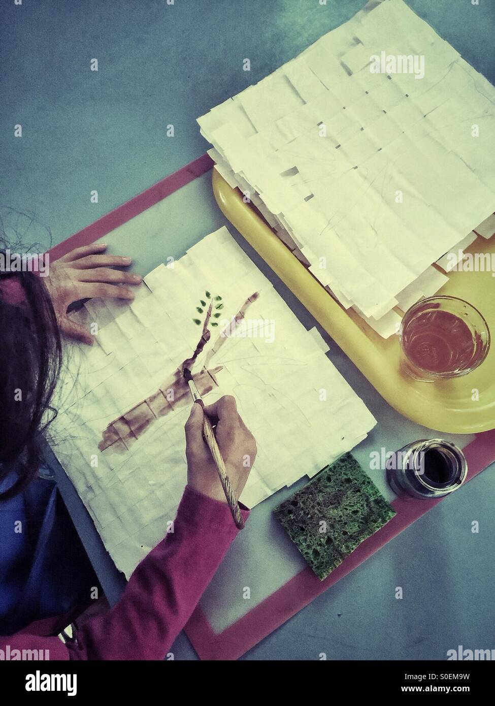 Child painting a tree on a handmade paper - Smartphone Captured Stock Image