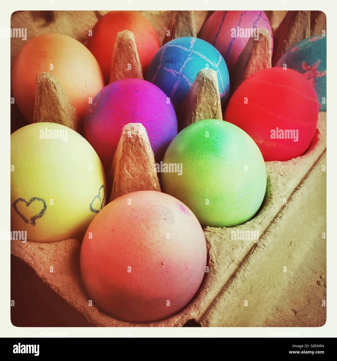 Brightly colored hard boiled eggs are in an egg carton. Stock Photo