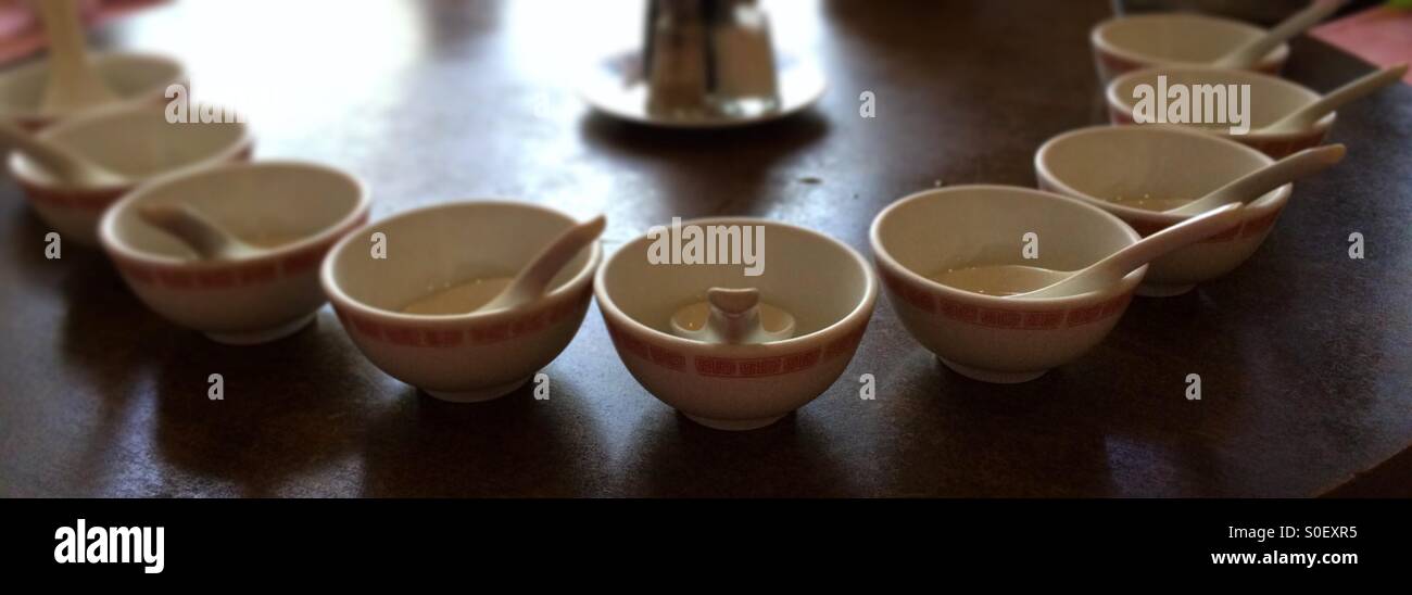 Empty Chinese bowls with spoons in them on a table. - Smartphone Captured Stock Image