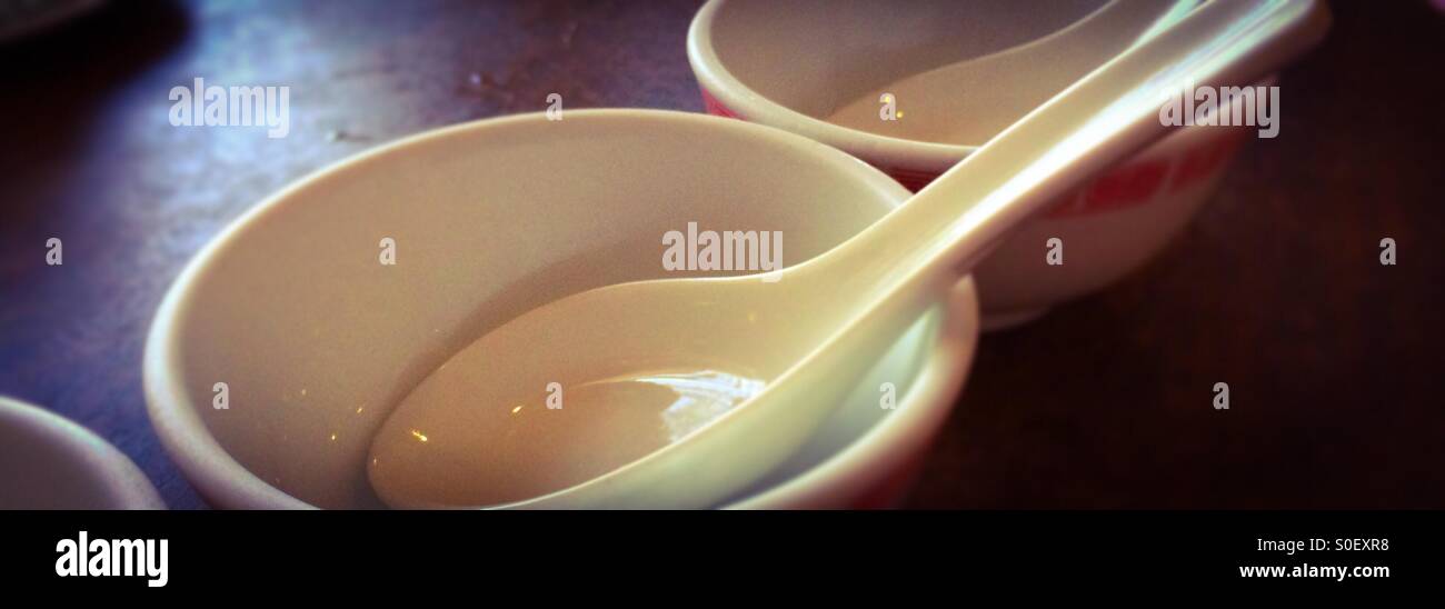 Empty Chinese bowls with spoons in them on a table. - Smartphone Captured Stock Image