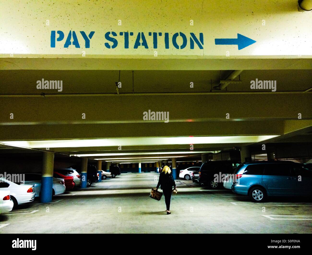 A blonde woman returns to her car after shopping at the mall - Smartphone Captured Stock Image