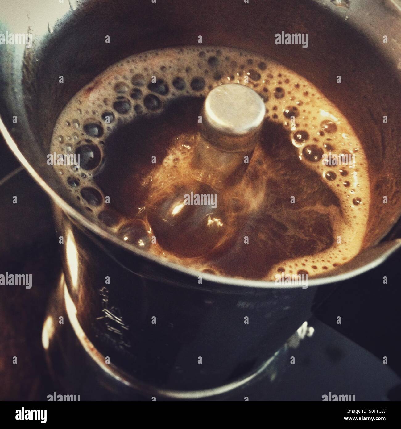 Fresh, hot, steaming espresso in an Italian Coffee Maker with Bubbles and a Rich Brown Colour Stock Photo