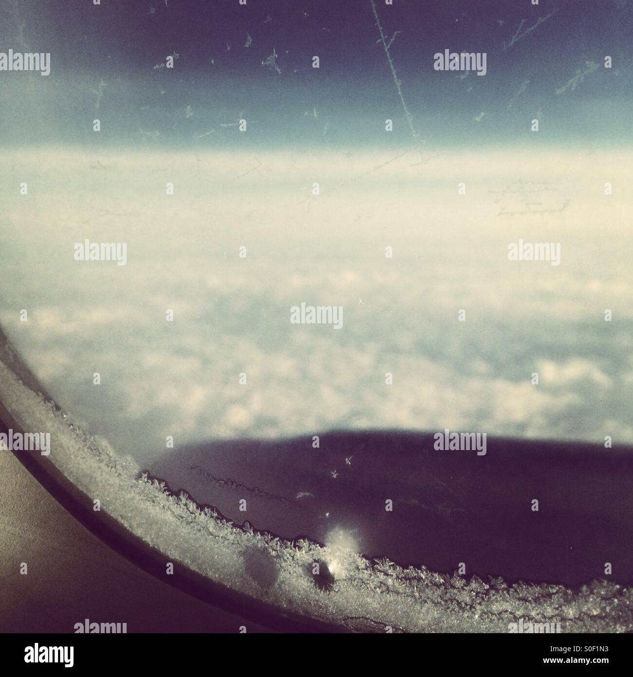 View from an airplane window above the clouds. - Smartphone Captured Stock Image