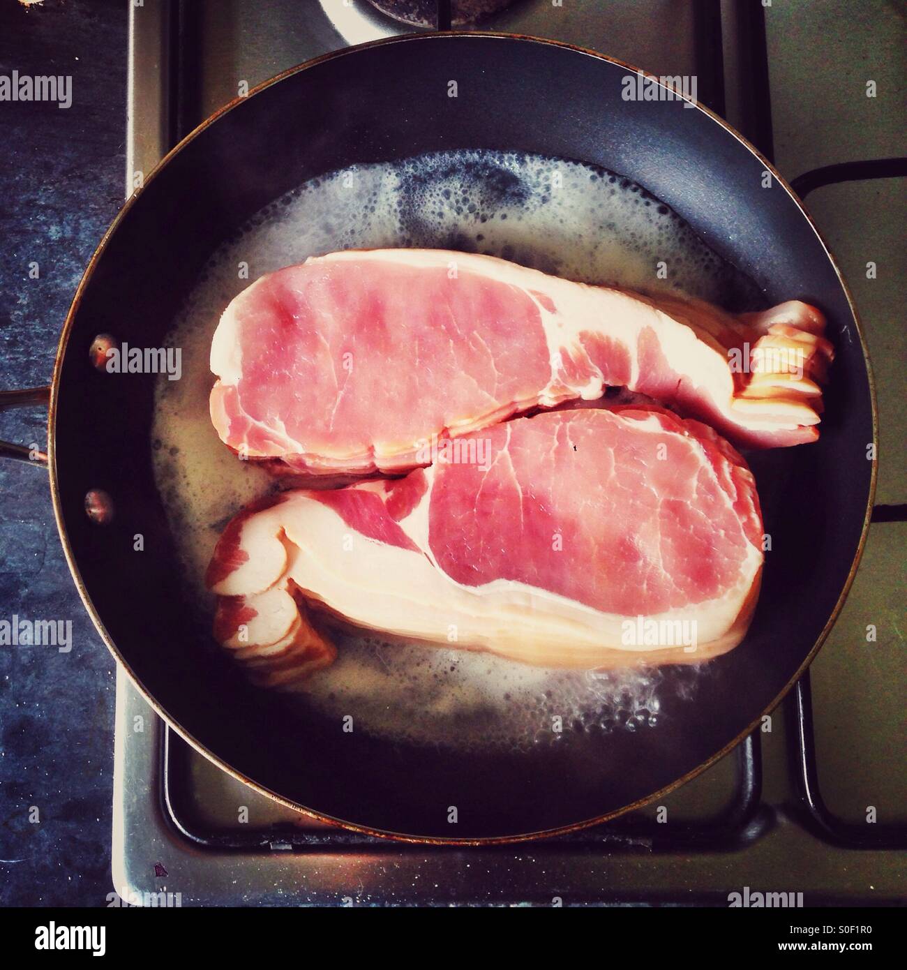 Bacon rashers cooking in a frying pan - Smartphone Captured Stock Image
