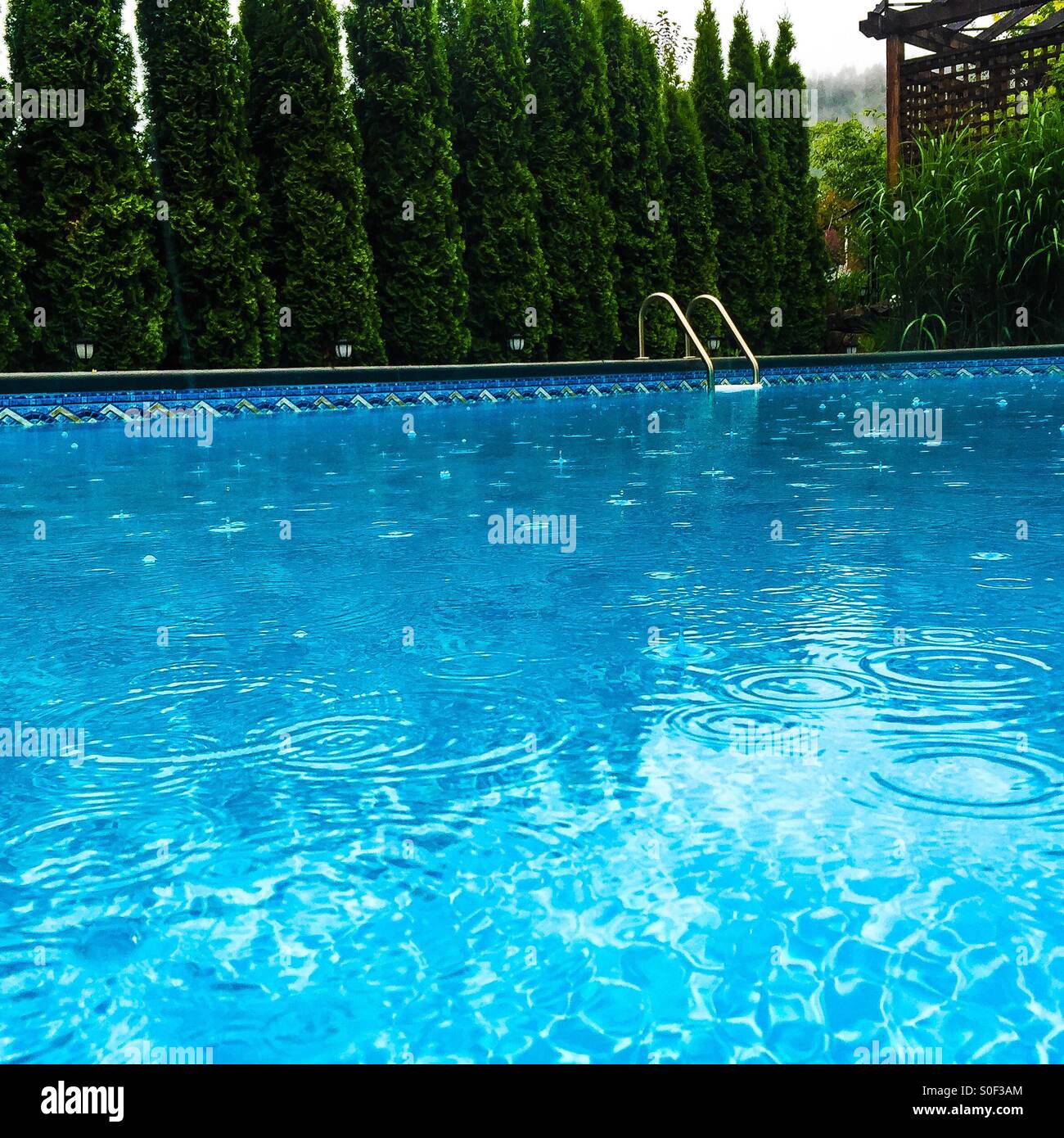 Outdoor swimming pool in the rain; the raindrops hitting the pool water