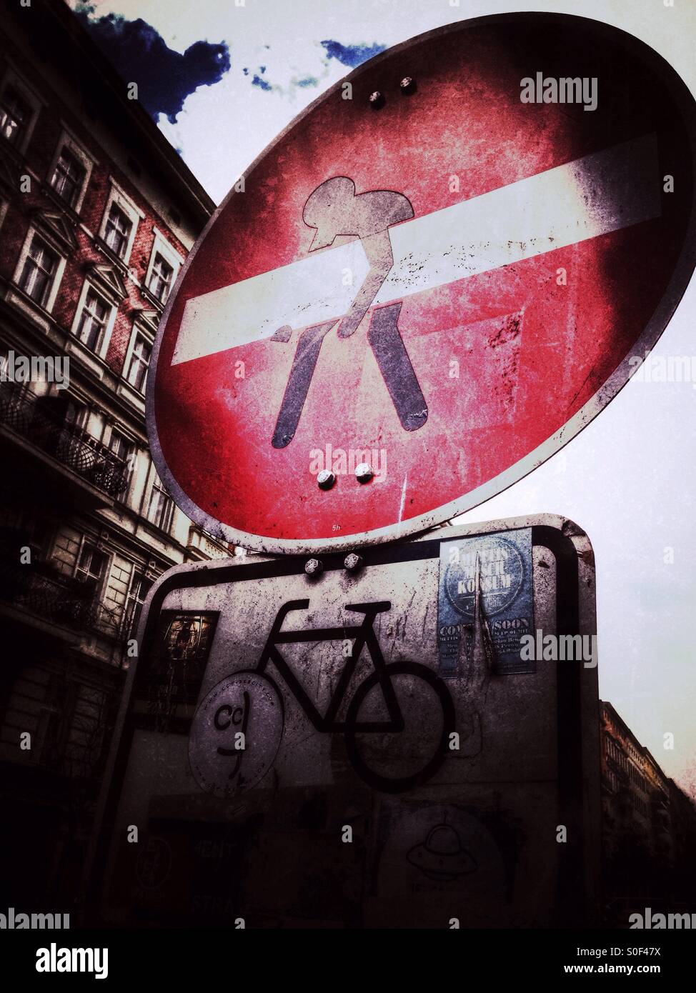 No entry Traffic Road Sign with Street Art of a Male Figure Carrying the line Like a Beam or a Bar and a Bicycle sign - Smartphone Captured Stock Image