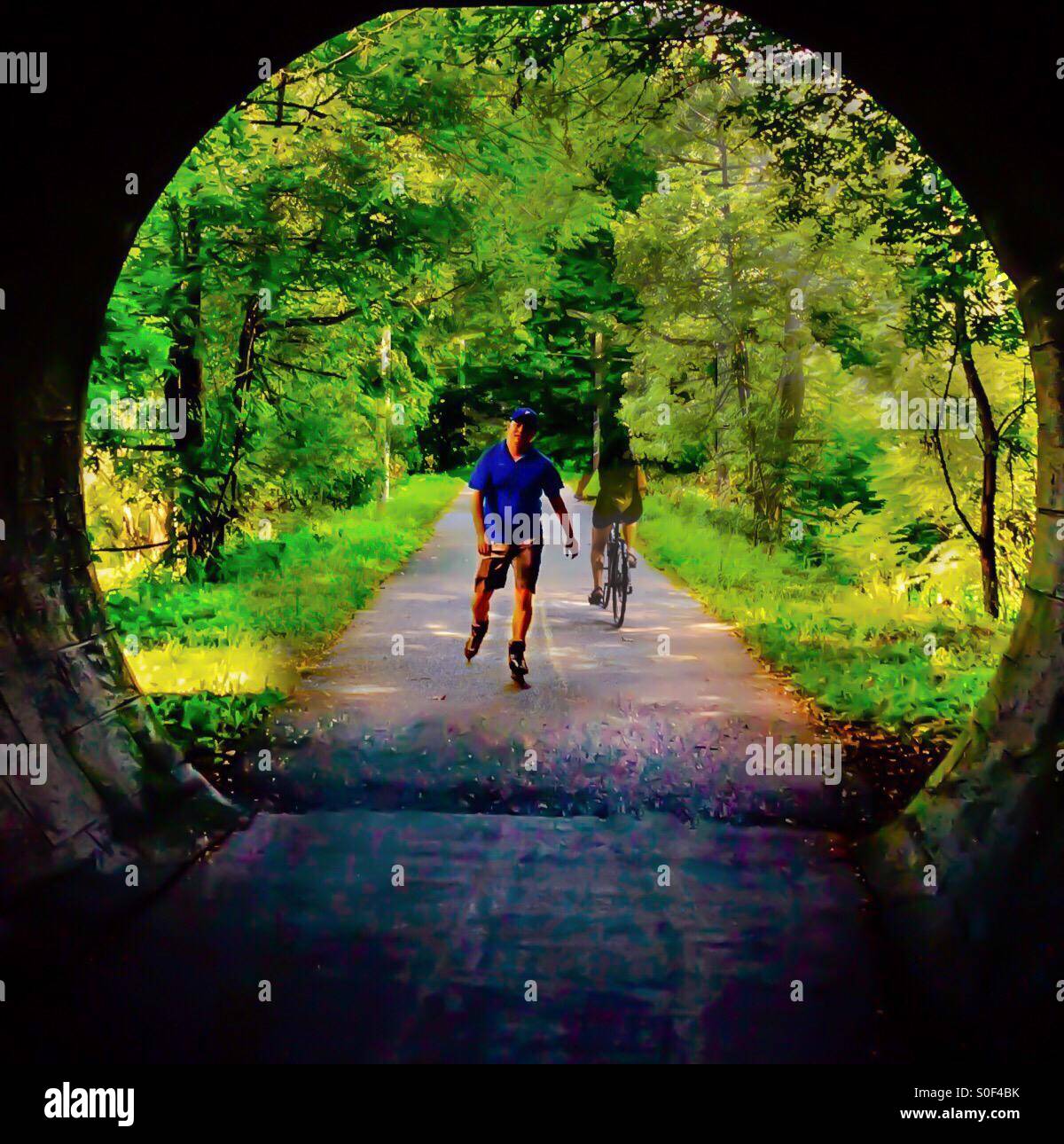 Summer Outdoors. Rollerblader coming and cyclist going. A view from a tunnel, Ontario, Canada. Motion. Movement. Activity - Smartphone Captured Stock Image