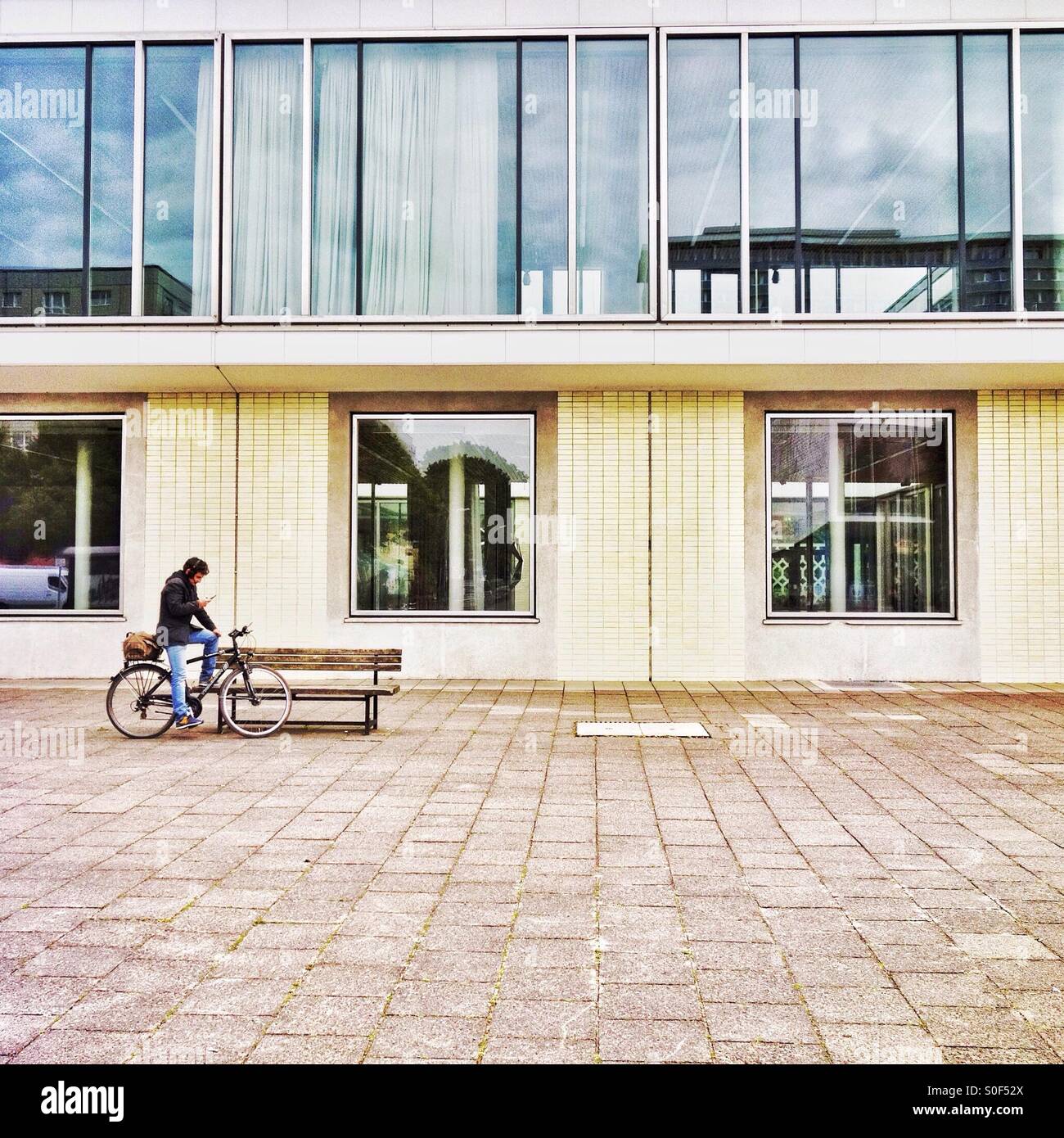 East Berlin building and a cyclist checking his phone - Smartphone Captured Stock Image