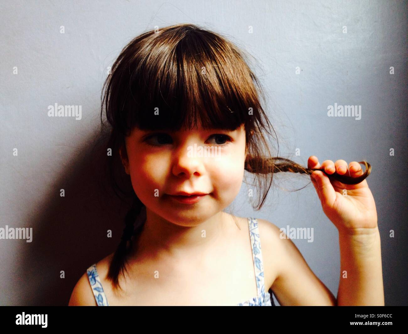 3-year old girl holding her pigtails Stock Photo