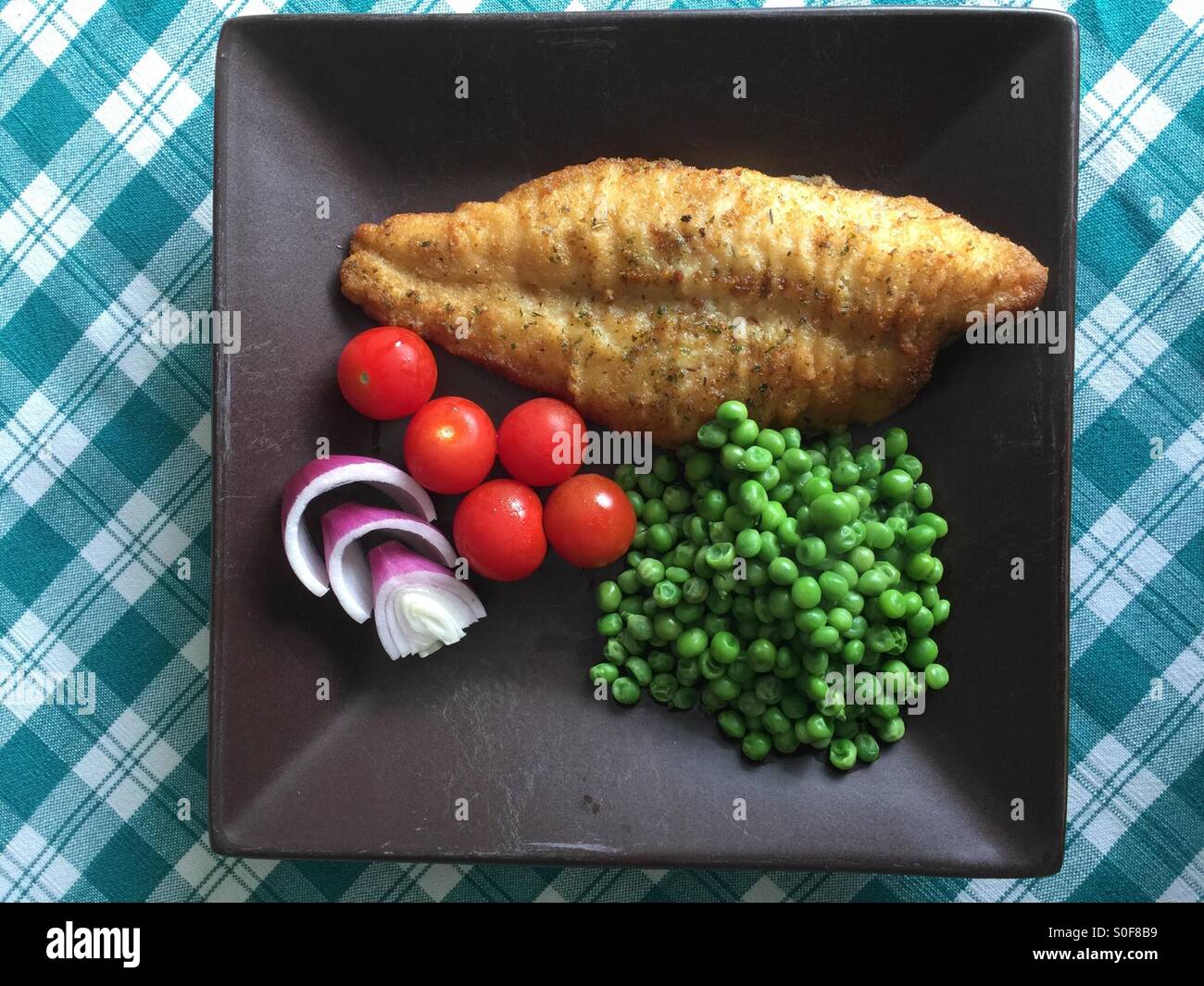 Healthy meal of fish,peas,onions and tomatoes on a square brown plate - Smartphone Captured Stock Image