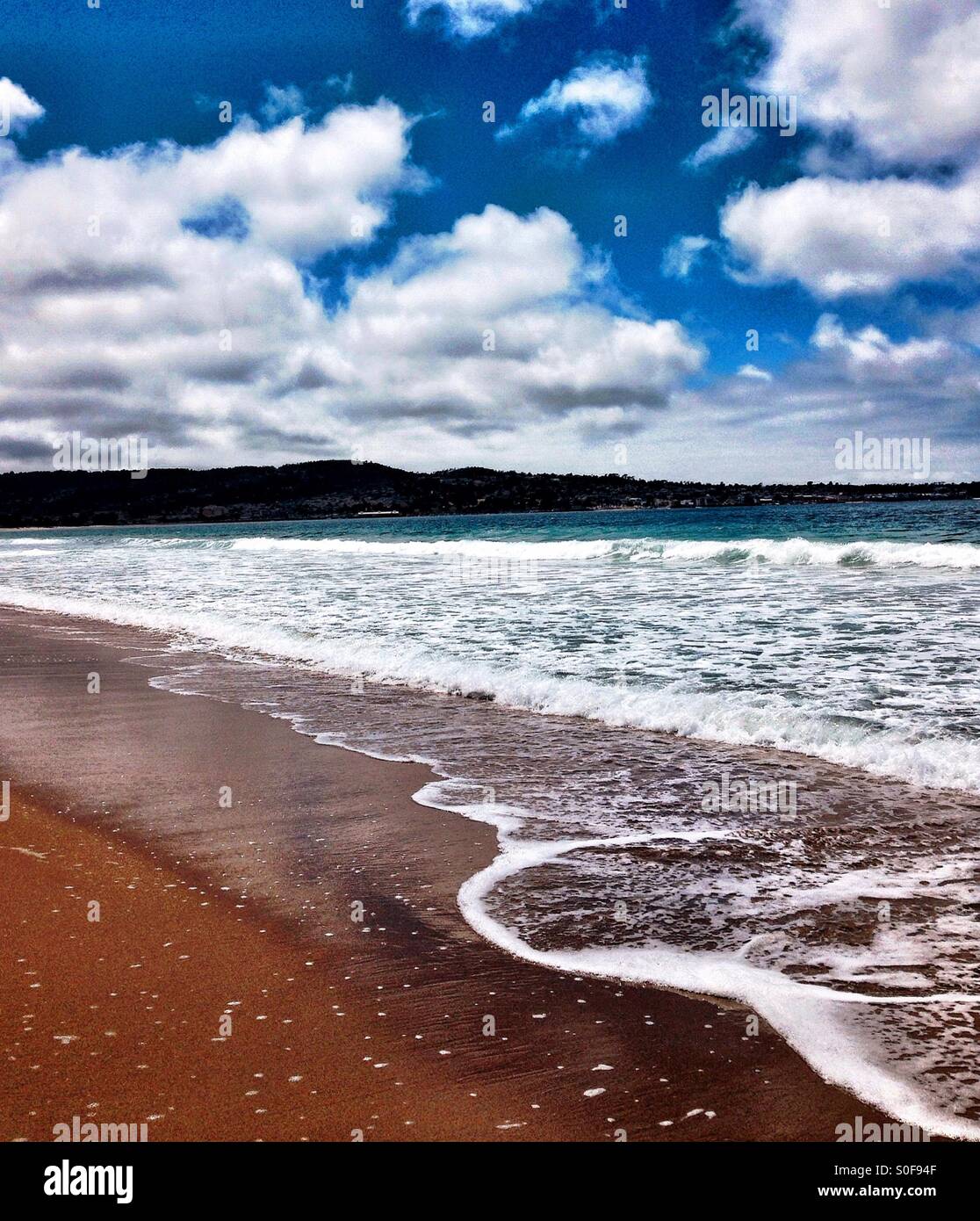 Gentle surf on Pacific Ocean beach with puffy clouds overhead - Smartphone Captured Stock Image