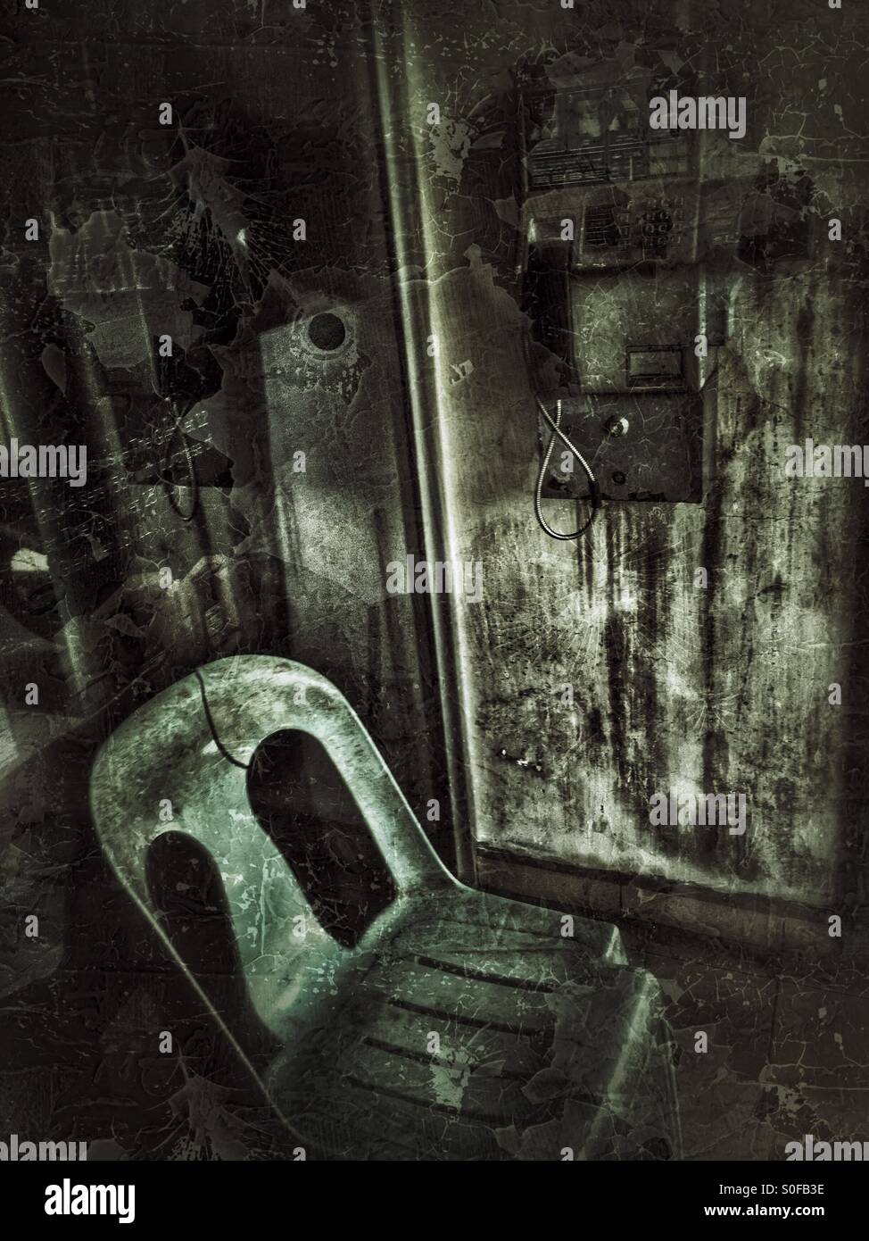 An old telephone on the wall and a plastic chair. - Smartphone Captured Stock Image