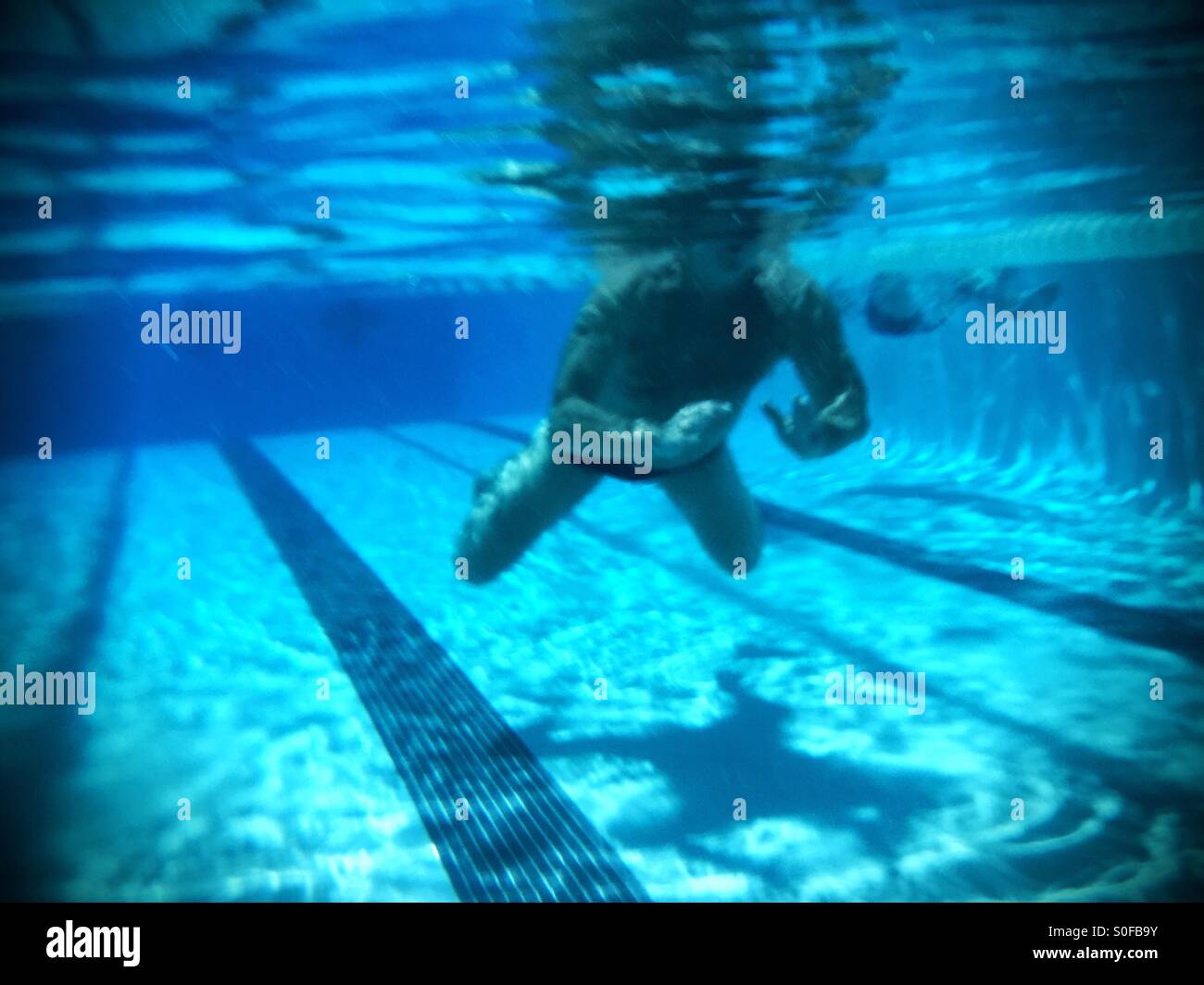 Swimmer swimming breaststroke underwater view with watery shadow, reflections. - Smartphone Captured Stock Image
