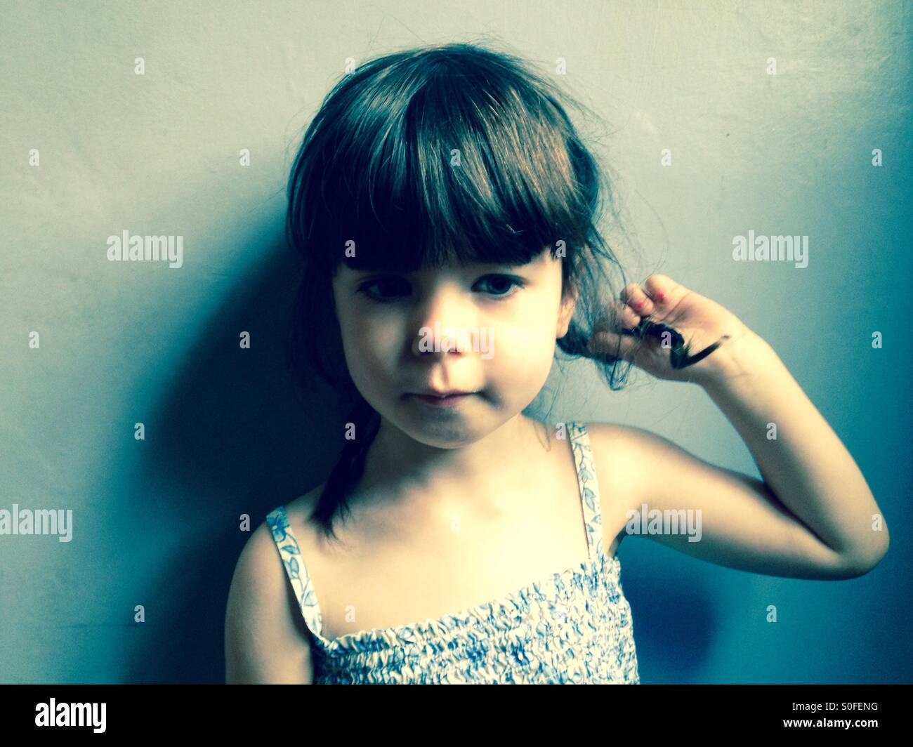 3-year old girl playing with her hair - Smartphone Captured Stock Image