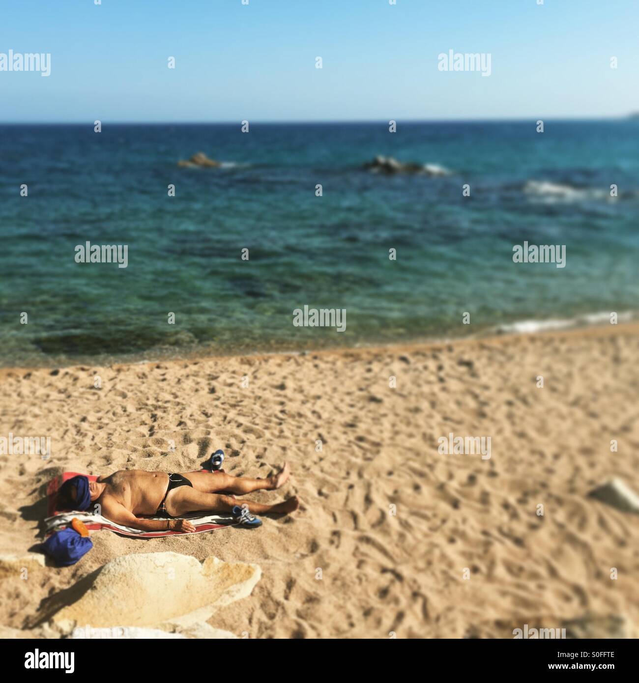 Man sunbathing alone, Costa Brava, Spain - Smartphone Captured Stock Image