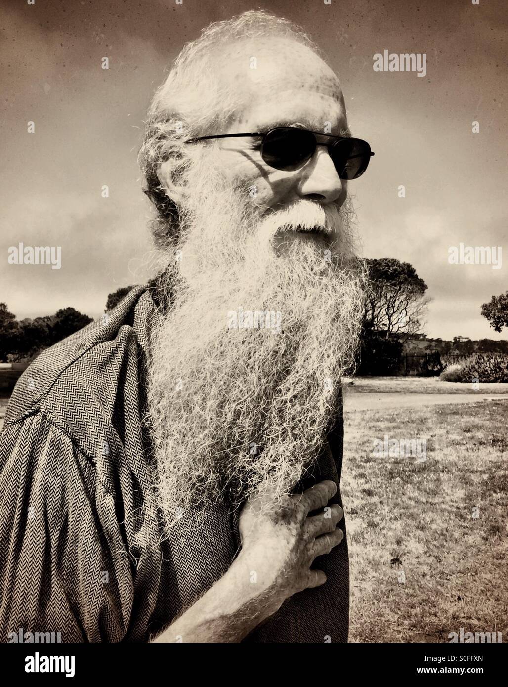 Elderly man with long white gray beard, outdoors in the morning, skies on the cusp of sun and fog. Sepia tone. San Francisco, California, USA. - Smartphone Captured Stock Image