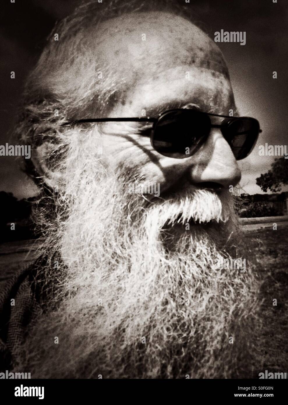 Portrait of an elderly gentleman with long white beard and sunglasses. Black and white vignette. San Francisco, California, USA. - Smartphone Captured Stock Image