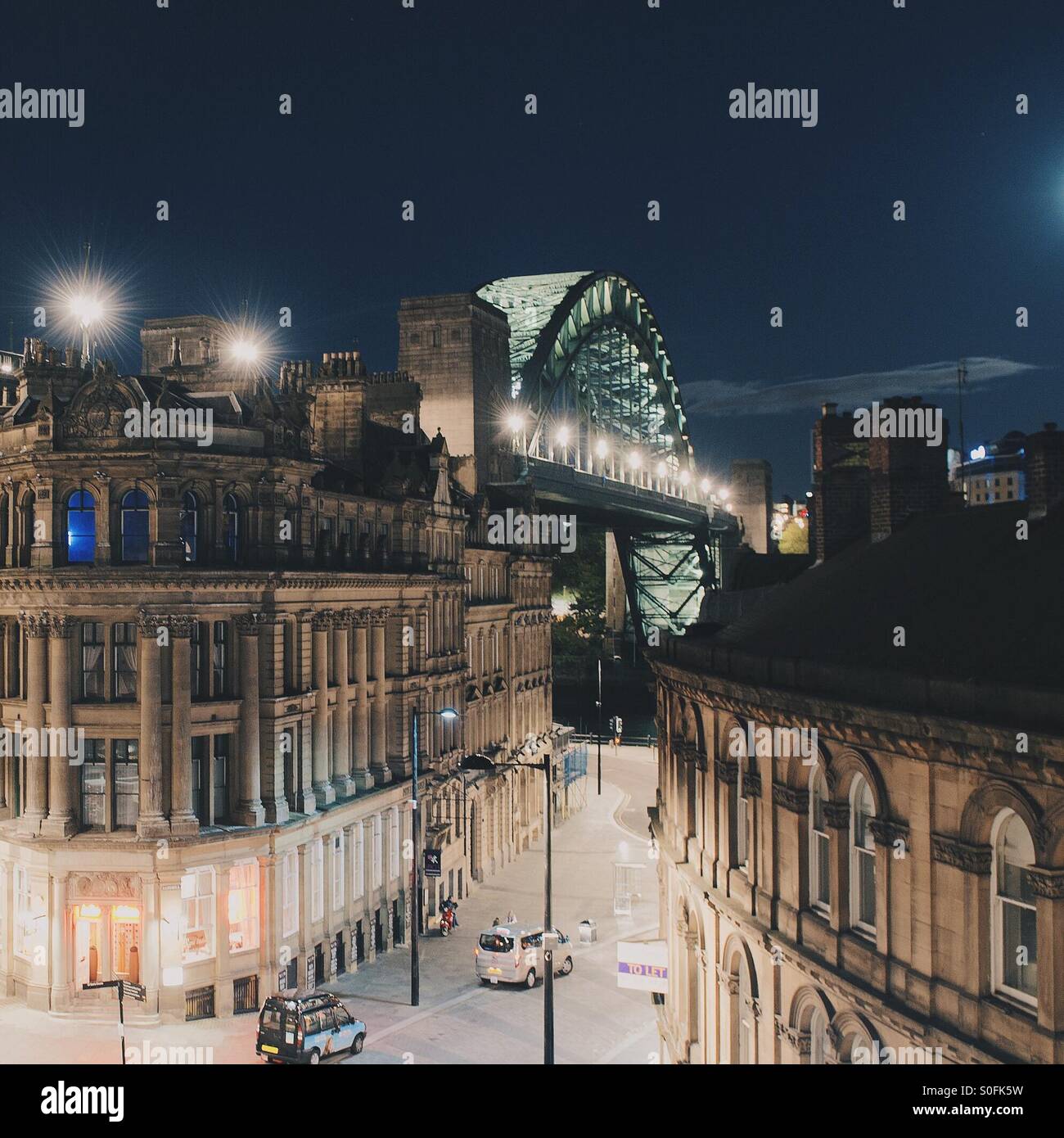 A view of the Tyne bridge in Newcastle looking down a city street at night - Smartphone Captured Stock Image
