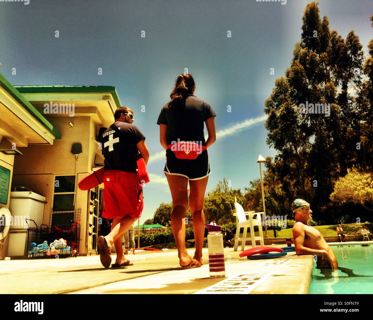 The outdoor swimming pool scene. Lifeguards on deck. Swimmers in the water. - Smartphone Captured Stock Image