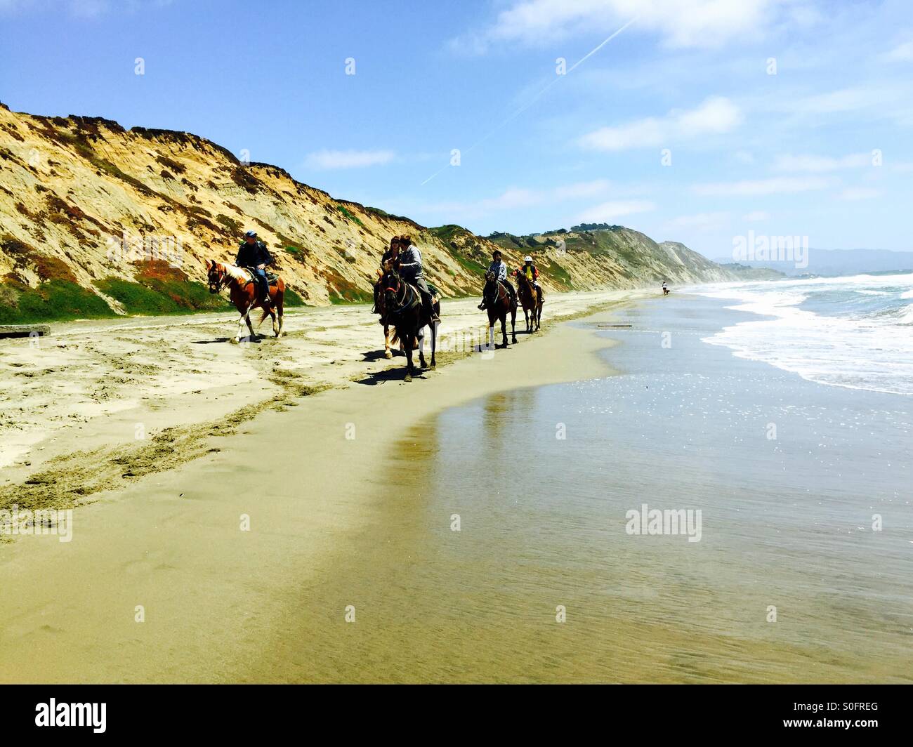 Horseback riders headed north on a seemingly endless stretch of Northern California beach. - Smartphone Captured Stock Image