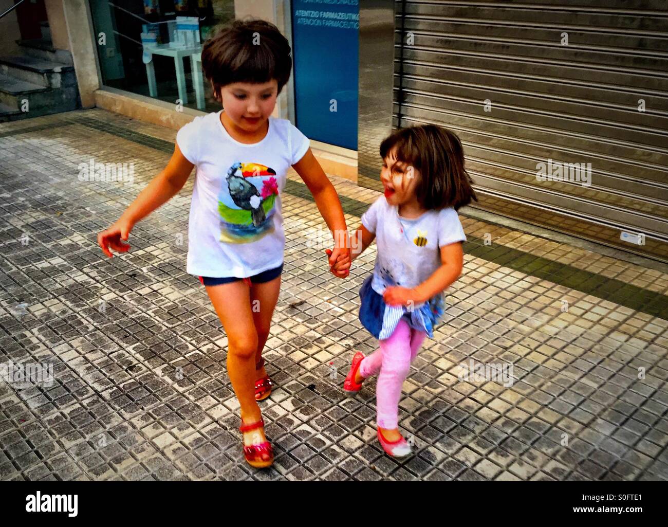 Sisters holding hands walking towards the camera - Smartphone Captured Stock Image
