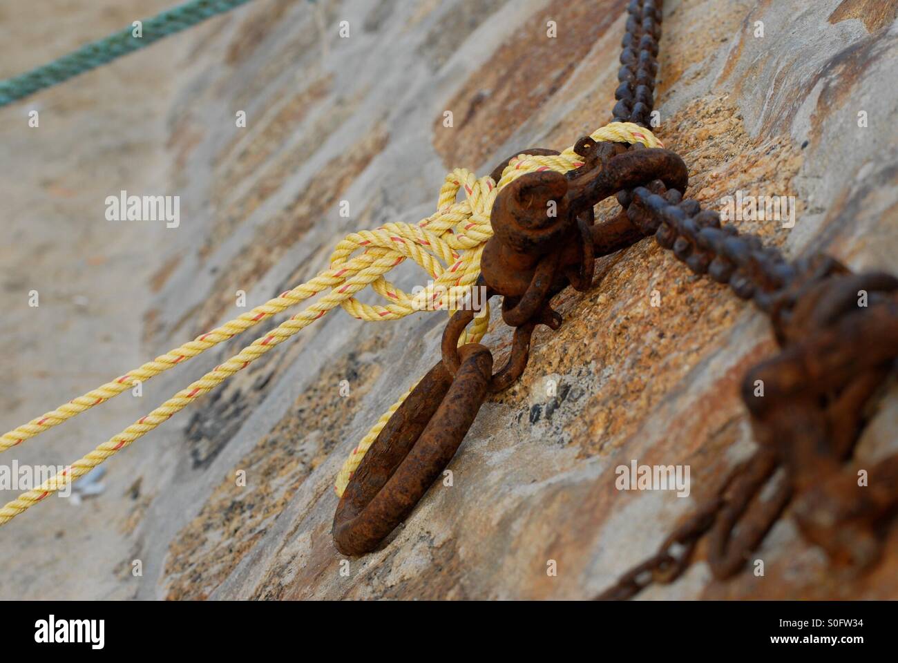Fisherman's knot on sea wall on rusty chain and loop Stock Photo