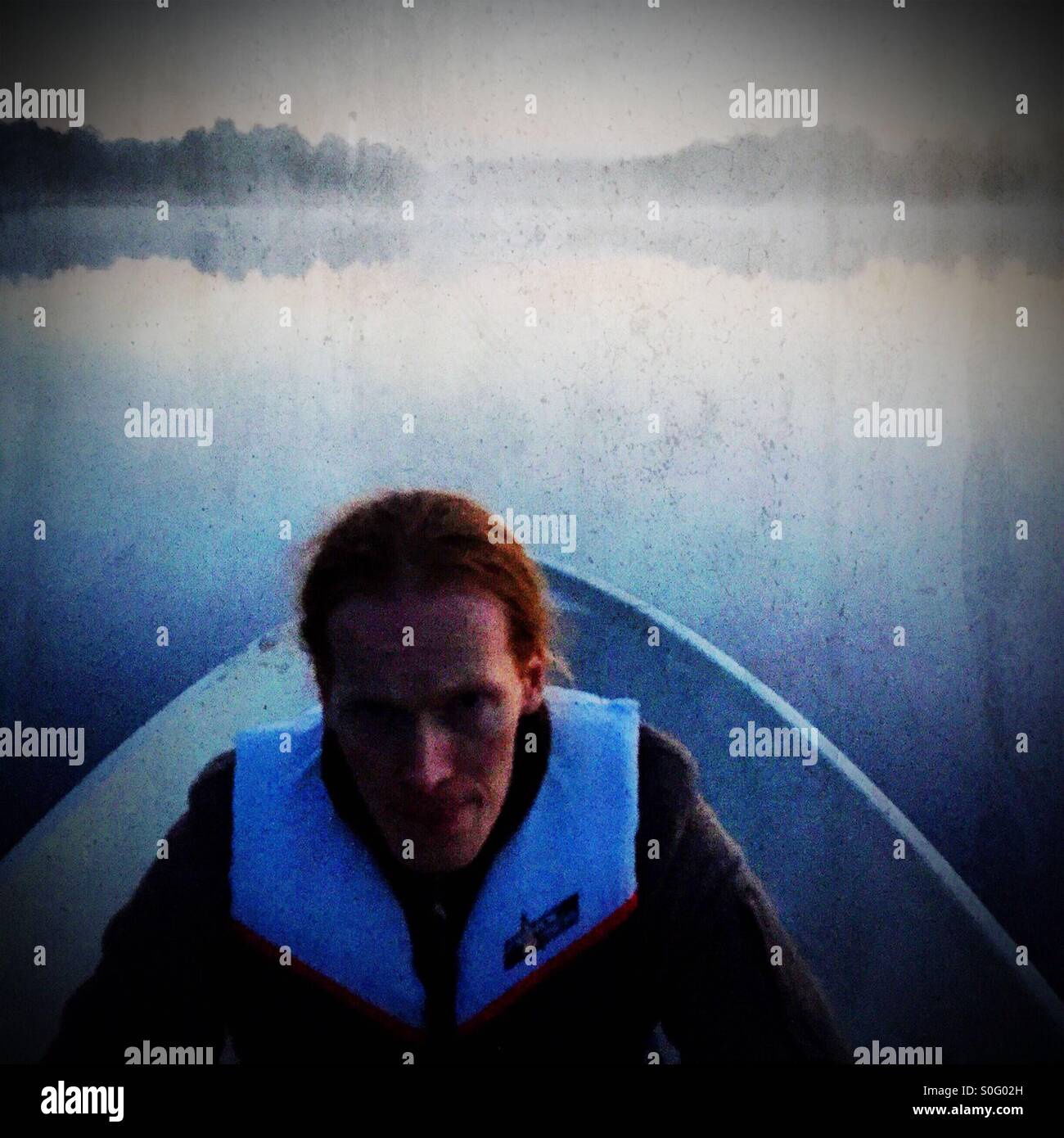 A red headed man rowing a boat Stock Photo