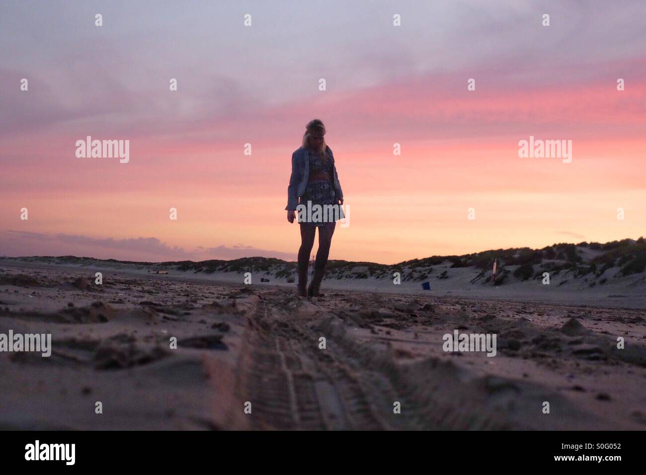 Young girl walking on a beach in the sunset Stock Photo