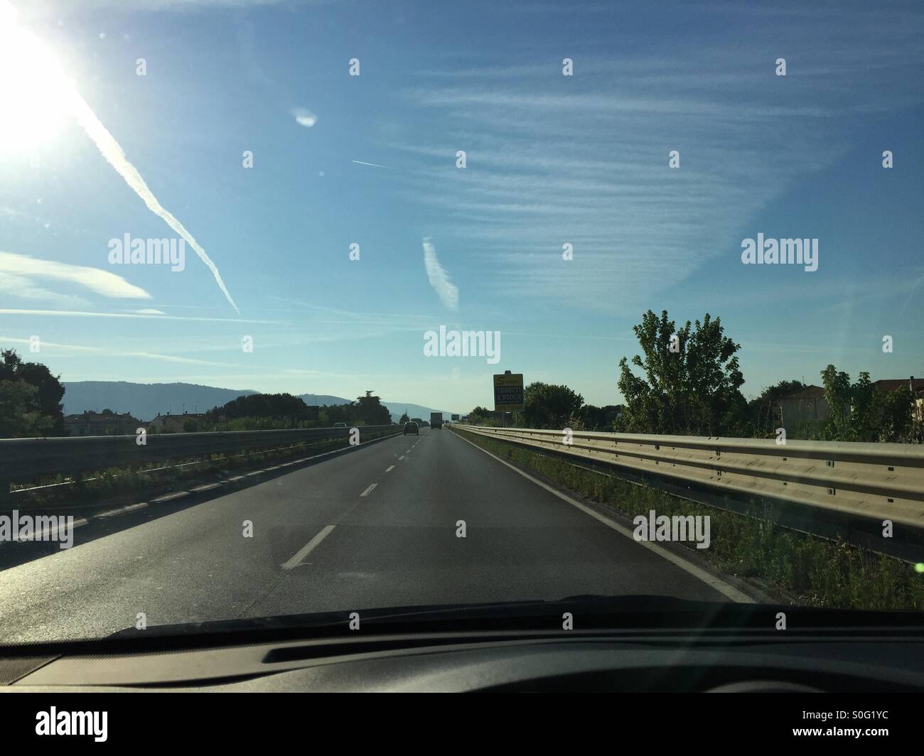 Two wakes of aircraft in the sky between strange clouds while I'm driving Stock Photo