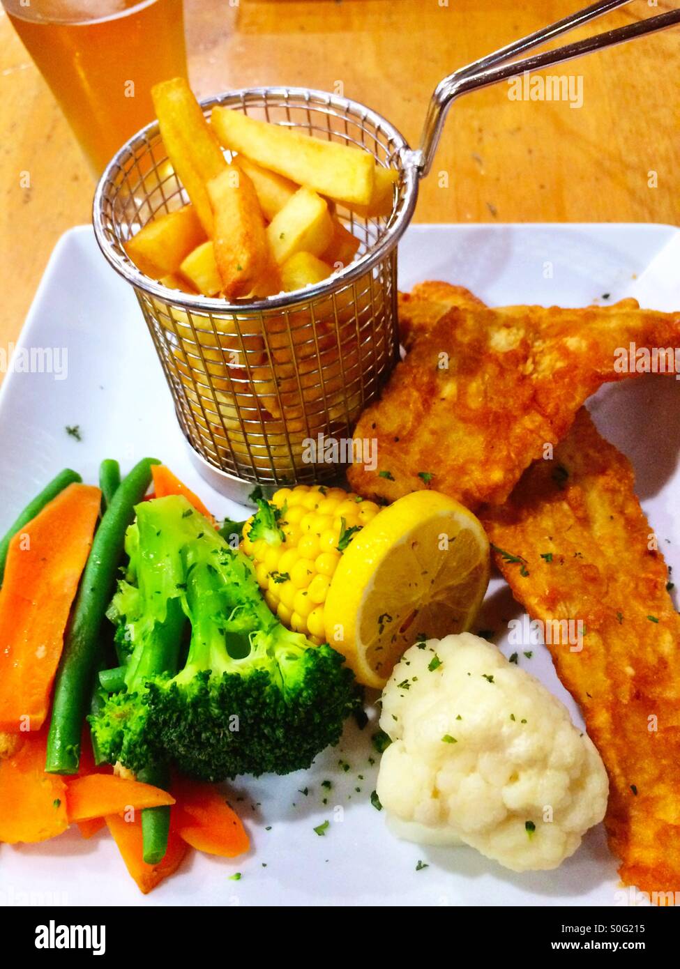 Typical Australian pub meal of fish and chips, vegetables and glass of beer Stock Photo