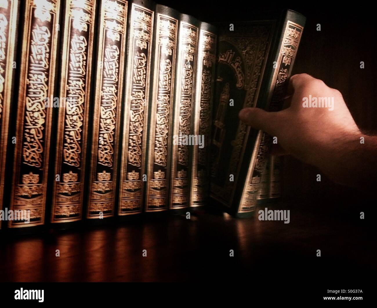 Man drawing the holy Quran out of the shelf - Smartphone Captured Stock Image